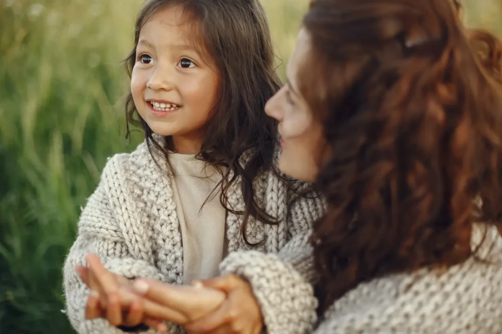 Young child smiling while spending time outdoors with a parent, highlighting a positive and nurturing family moment.