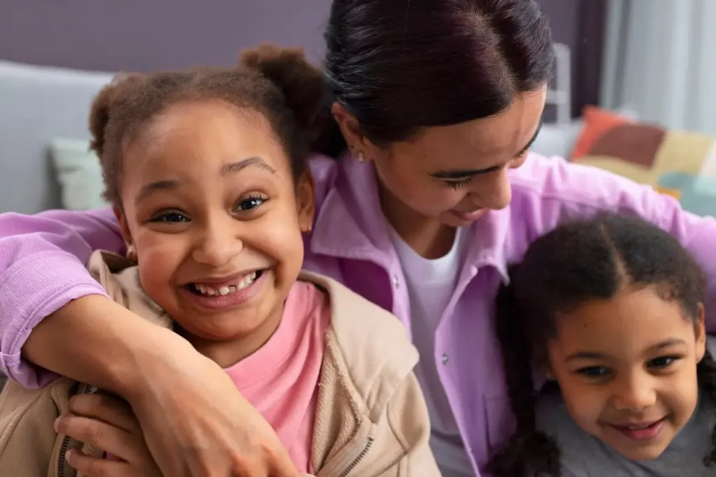 Parent embracing two smiling children on a couch, capturing a close and supportive family moment at home.
