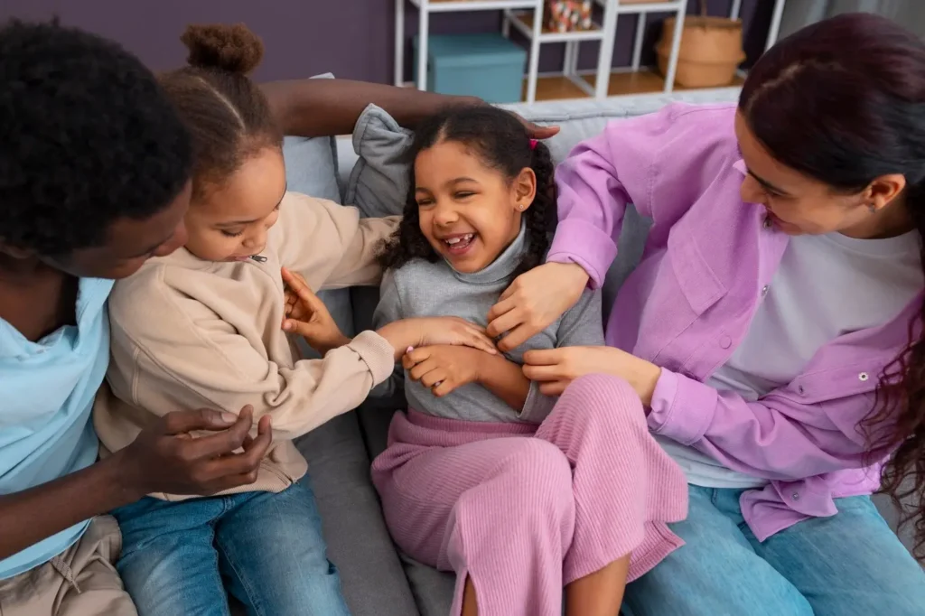 Two parents and their child laughing together on a couch, sharing a playful and affectionate family moment at home.